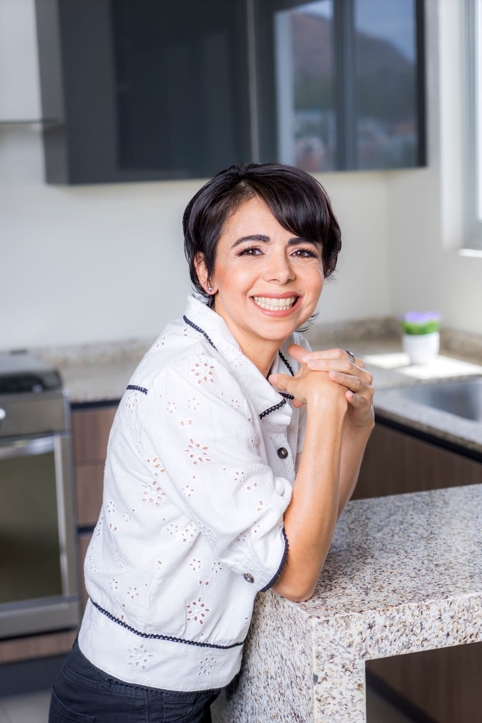 Independent cleaner smiling warmly in a bright modern kitchen, confident and ready for her next Ousie job